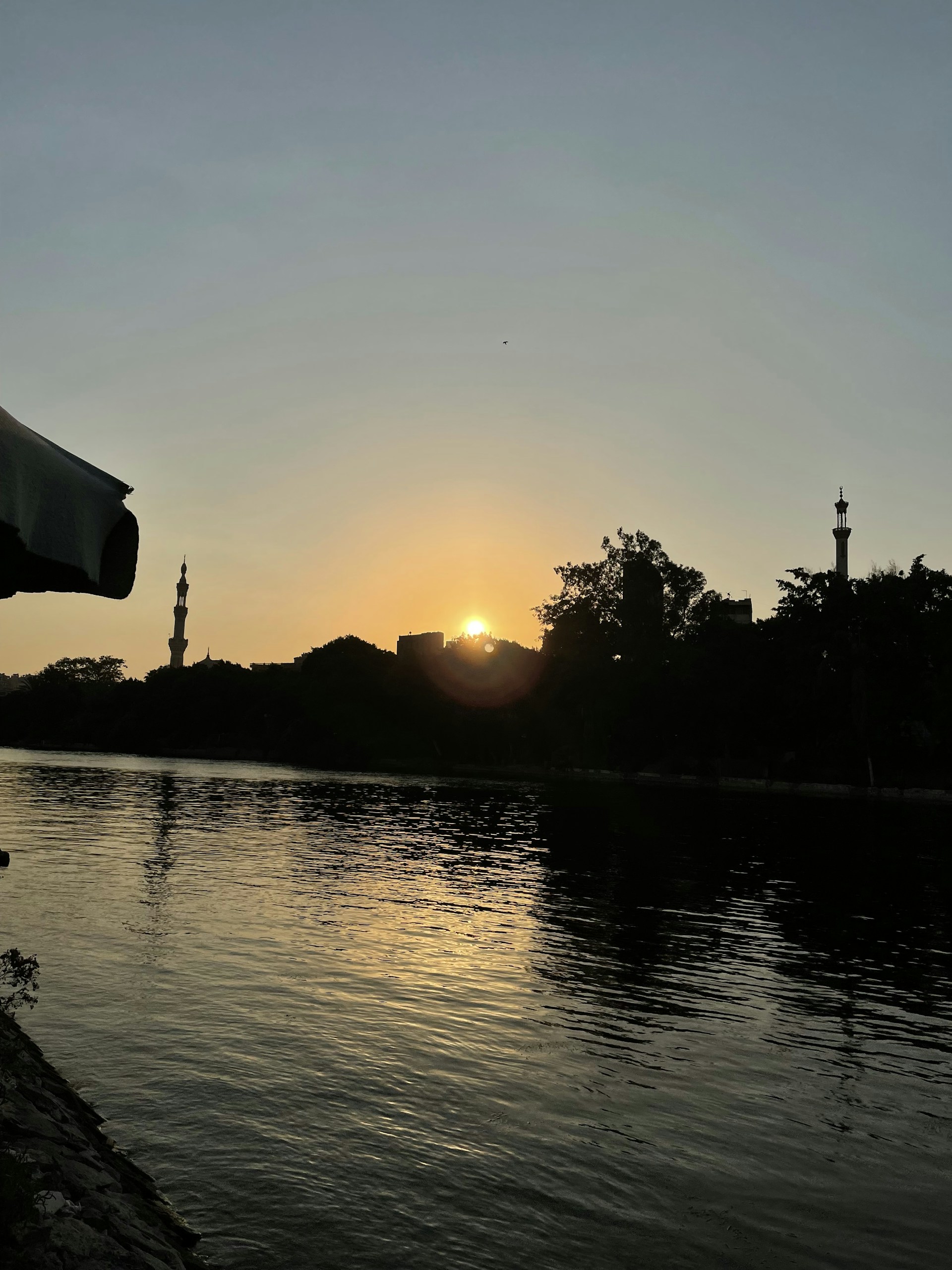 Sunset over a small riverside community in Rondônia, captured from above, highlighting the interplay of water, land, and human presence.
