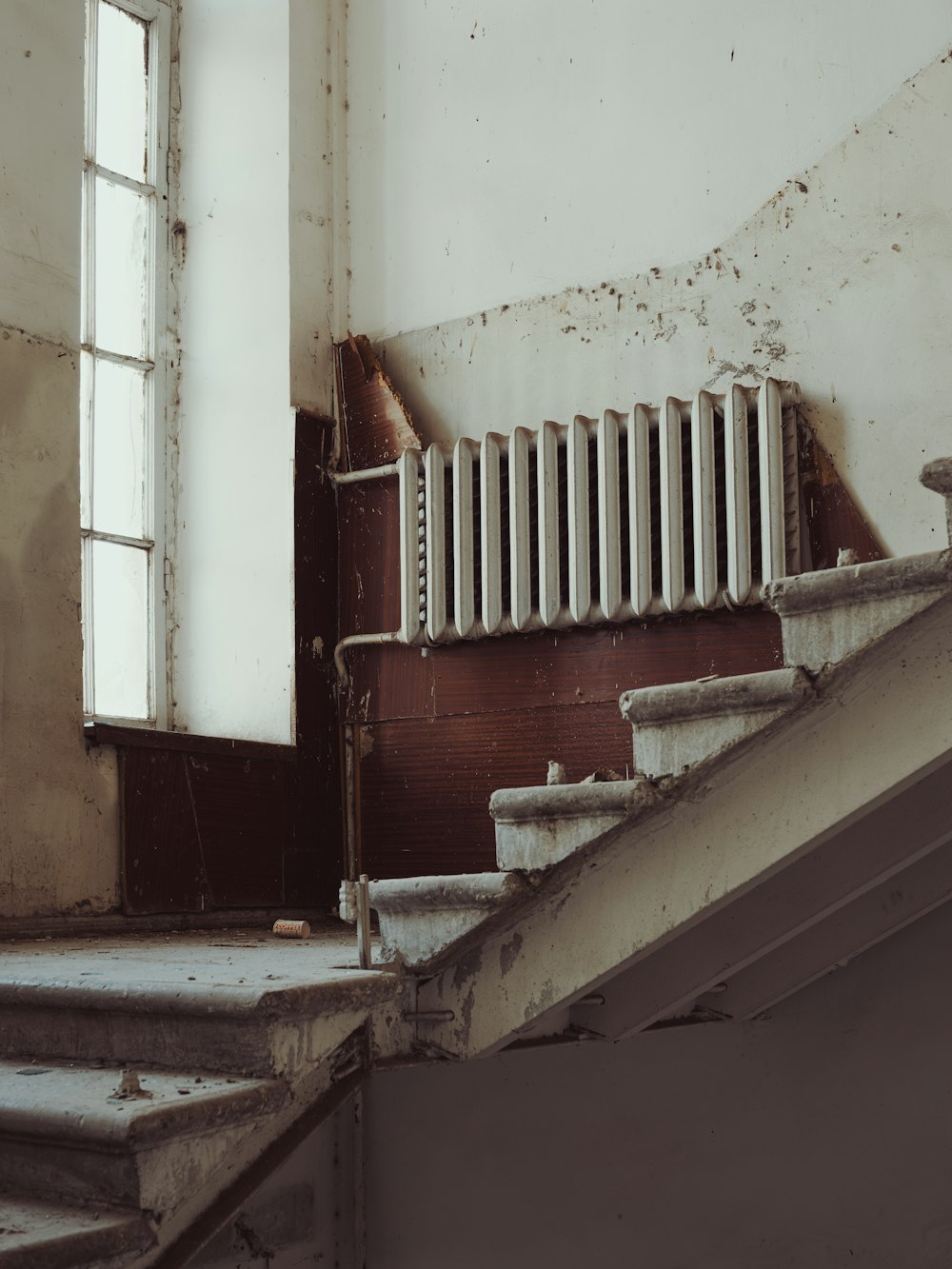 a rundown building with a radiator and a window