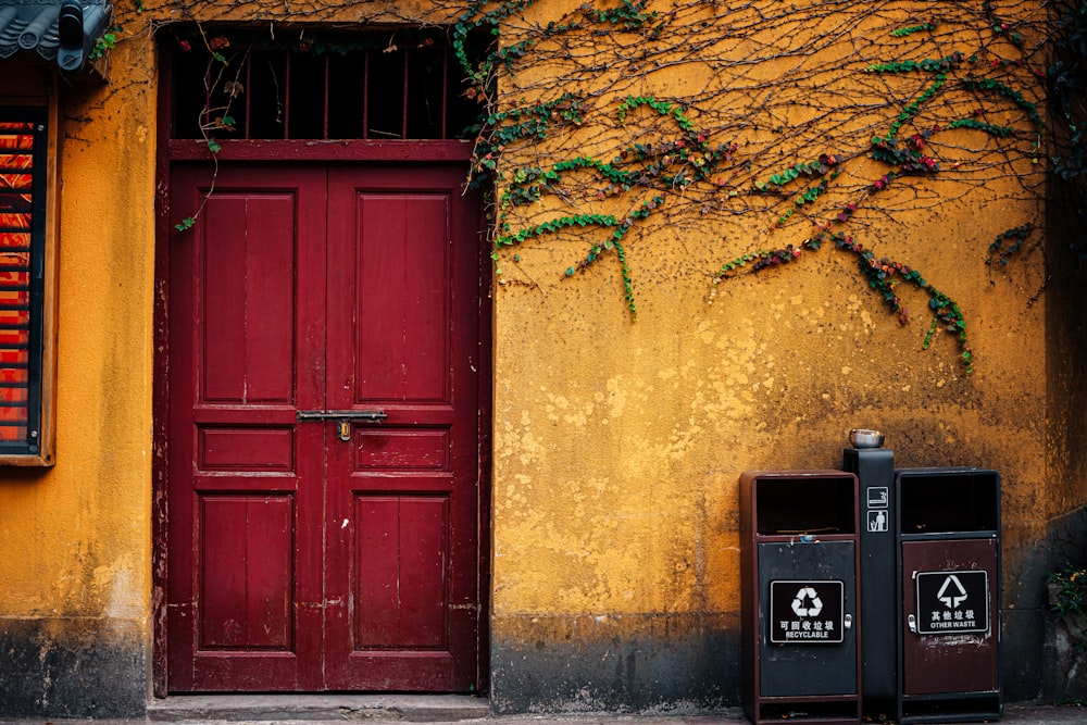a red door and two trash cans on a sidewalk