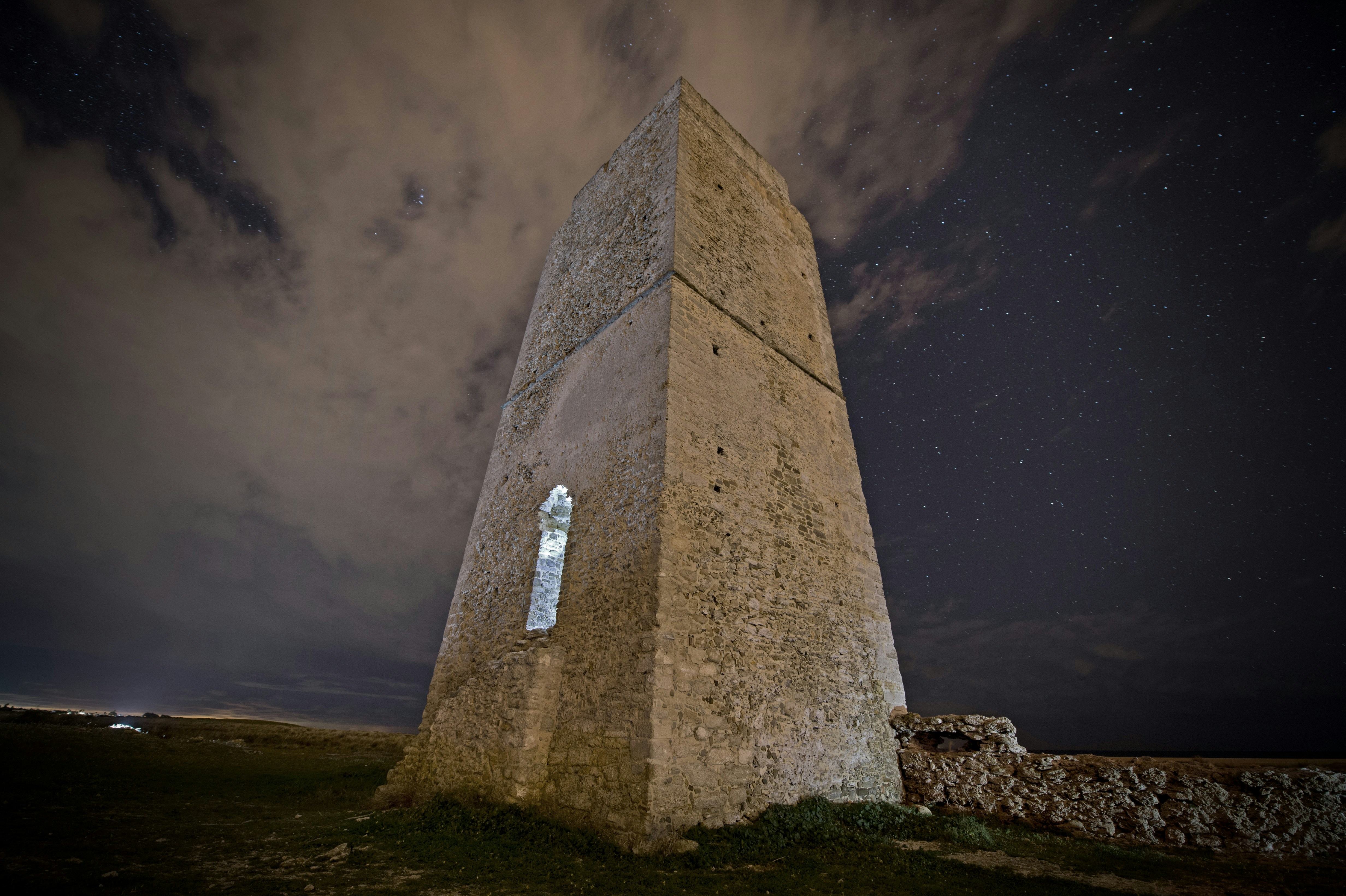 a tall stone tower sitting on top of a grass covered field