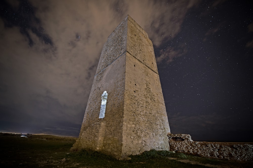 a tall stone tower sitting on top of a grass covered field