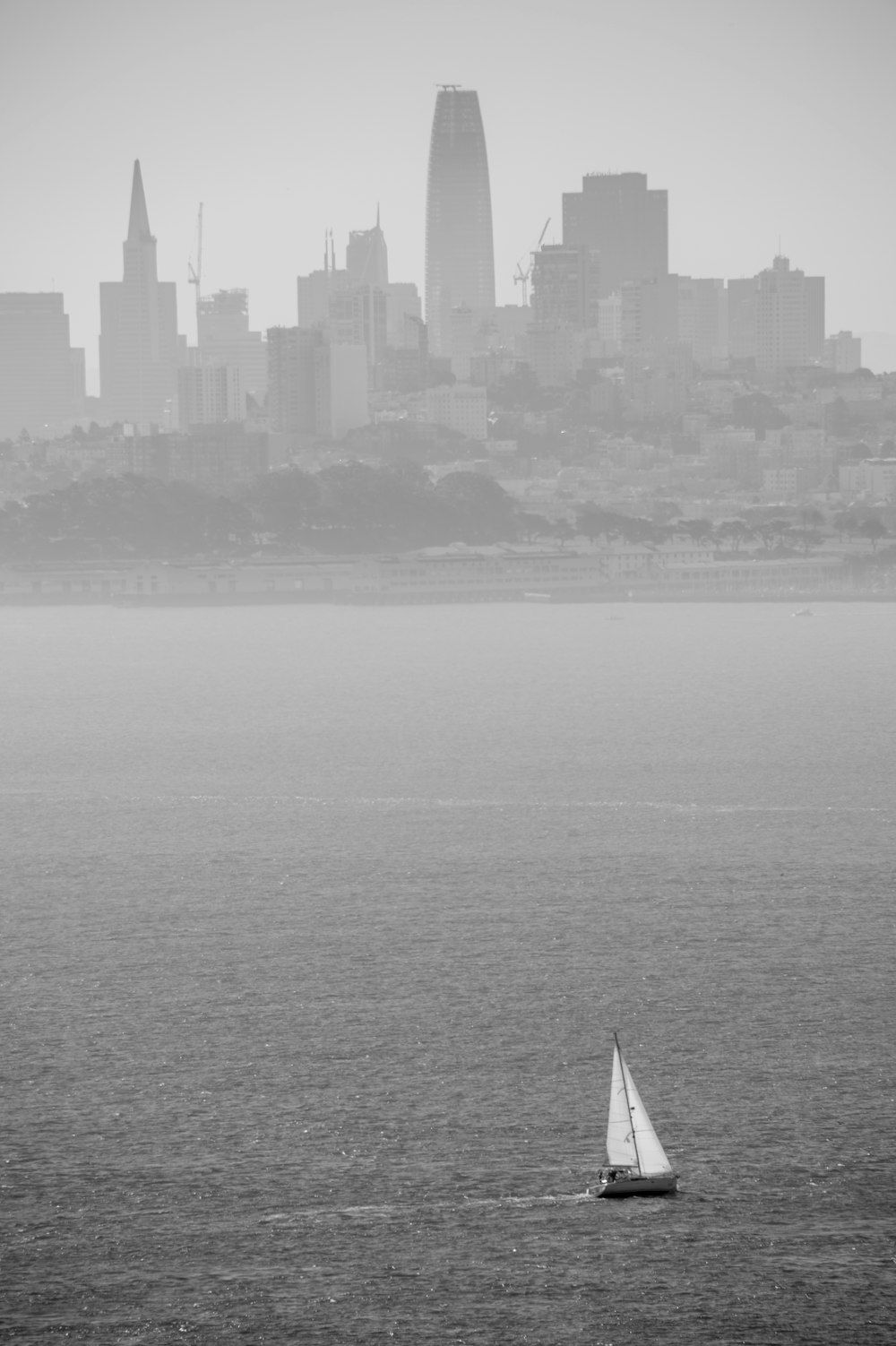 a sailboat in the water with a city in the background
