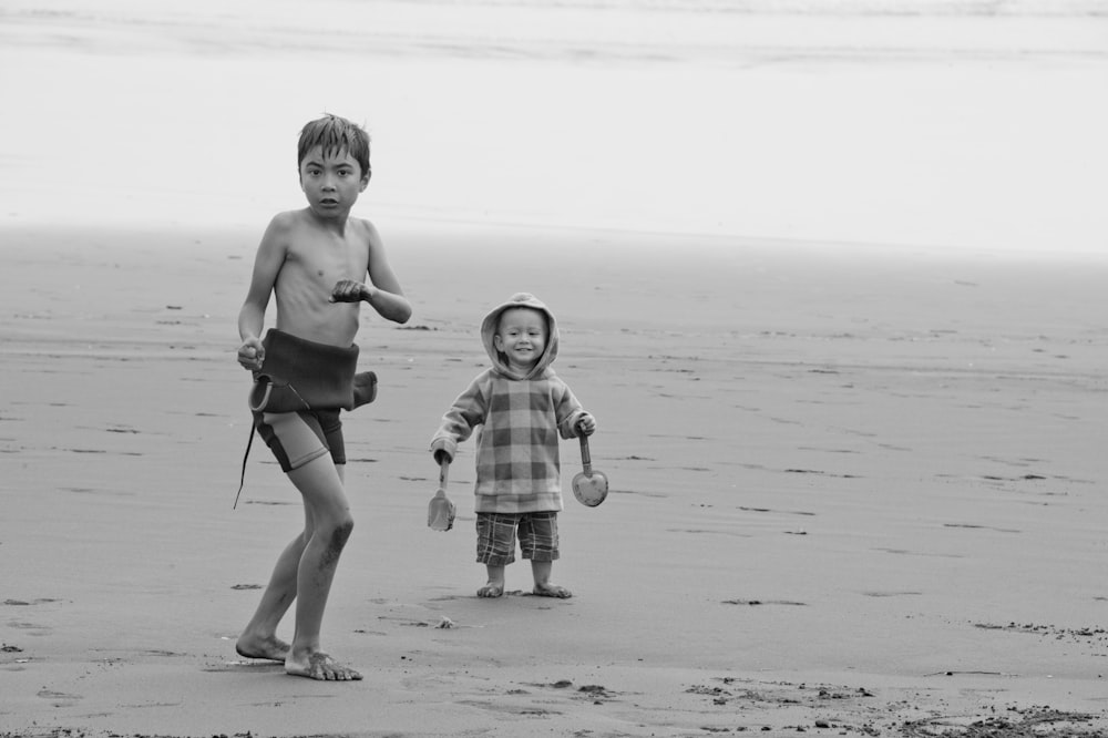 a couple of kids standing on top of a beach