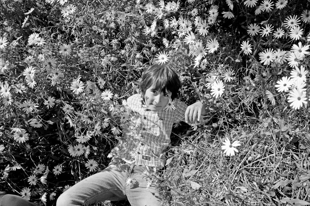 a young boy sitting in a field of flowers