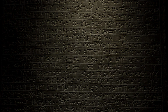 An ancient clay tablet with inscriptions glowing softly against a dark background.