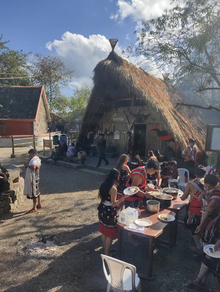 A vibrant community gathering with families sharing traditional meals and smiling together outdoors.