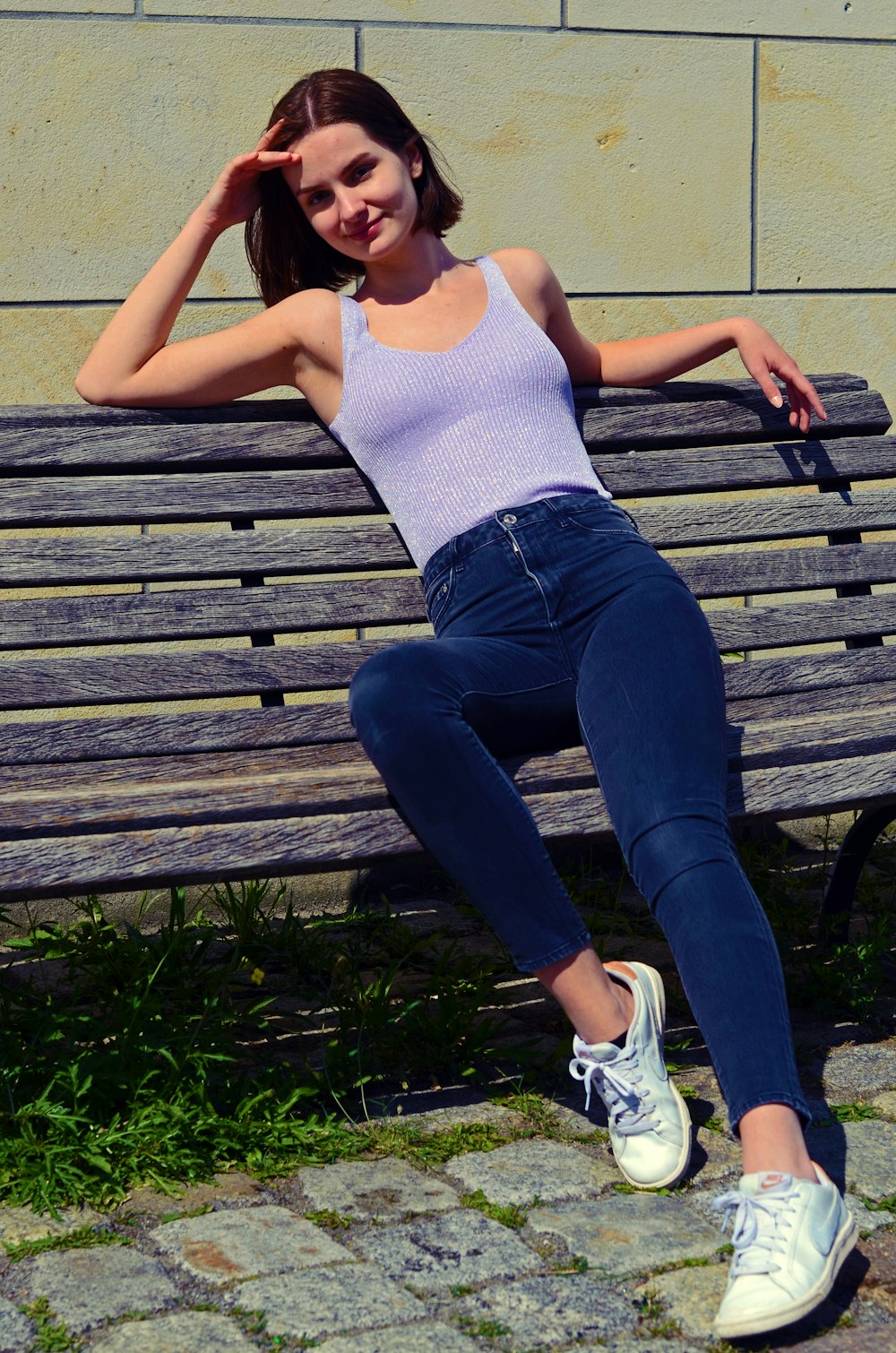 a woman sitting on a wooden bench in front of a building