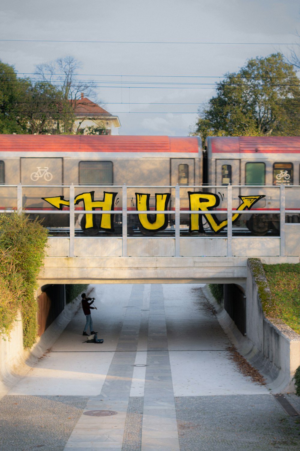 a person taking a picture of a train passing under a bridge