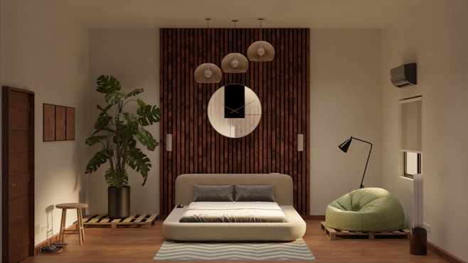 A modern living room features a low-profile sofa bed in the center, set against a wooden panel wall with a round decorative mirror. Above the sofa hang several pendant lights. To the left, a large potted plant adds a touch of greenery, next to a small wooden stool. On the right, a stylish floor lamp stands beside a green, plush armchair. The room also has an air conditioning unit and a window with a rolled-up blind.