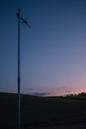 Keith setting up an antenna mast against a sunset backdrop in an open field.