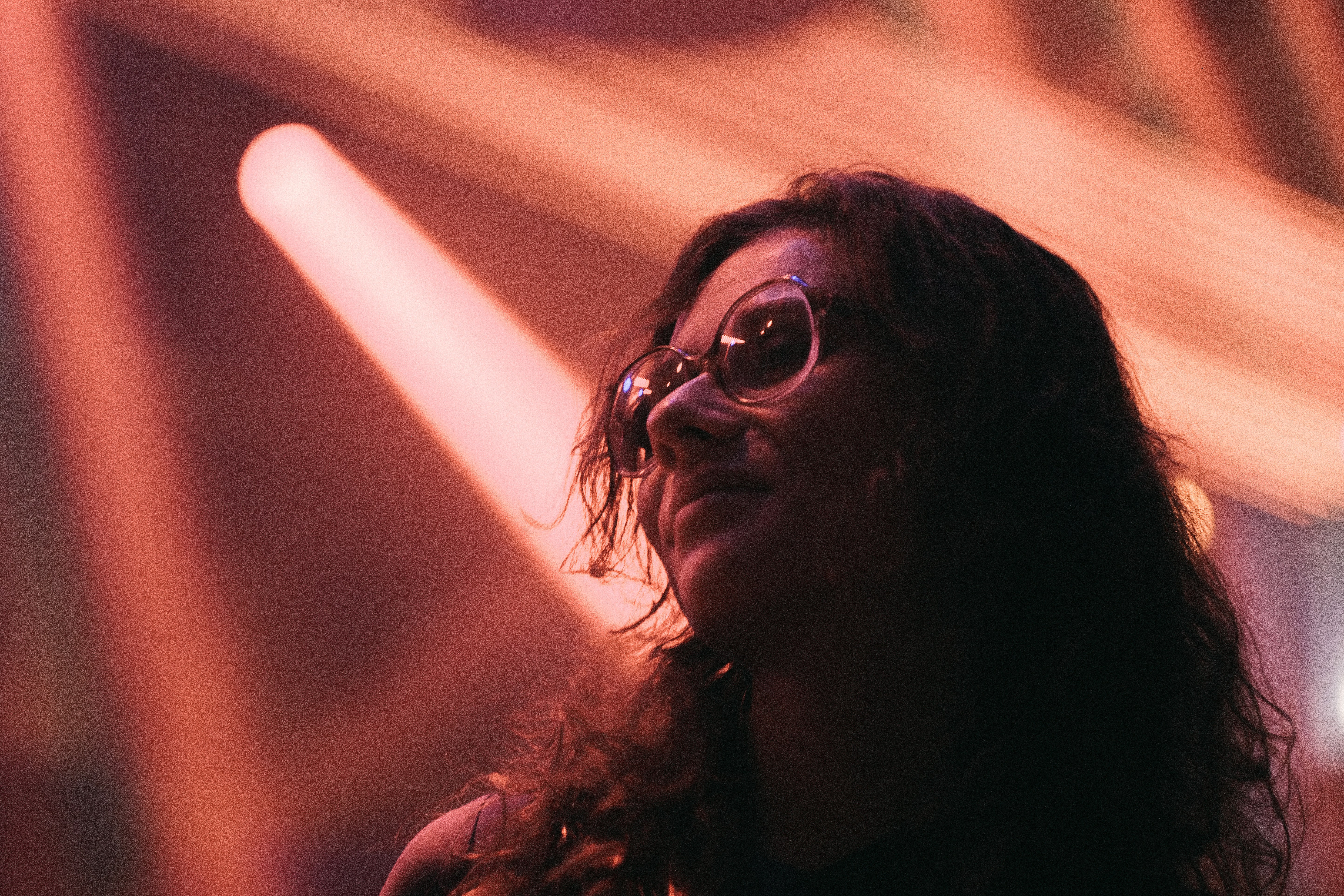 a woman wearing glasses standing in front of a stage
