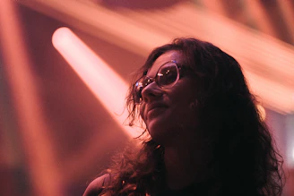 A whimsical photo of a woman with Hello Kitty hair pins laughing softly as sunlight filters through a window.