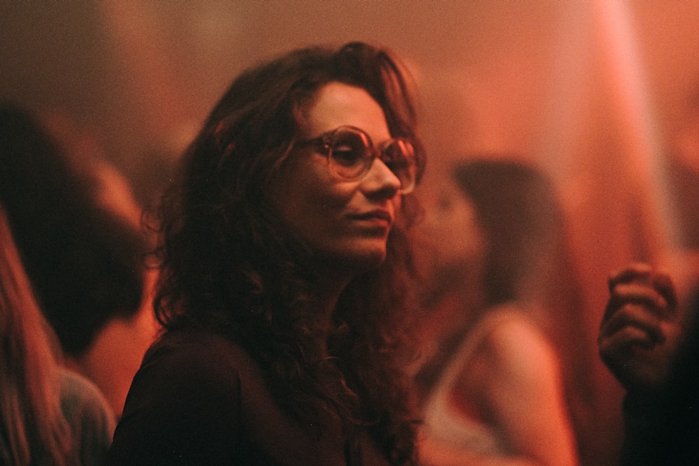 a woman with glasses standing in a crowd