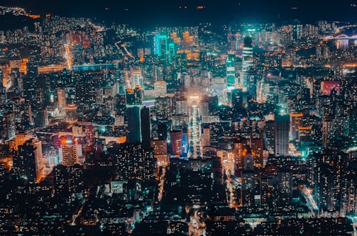 A bustling cityscape at night with glowing lights and lively streets.