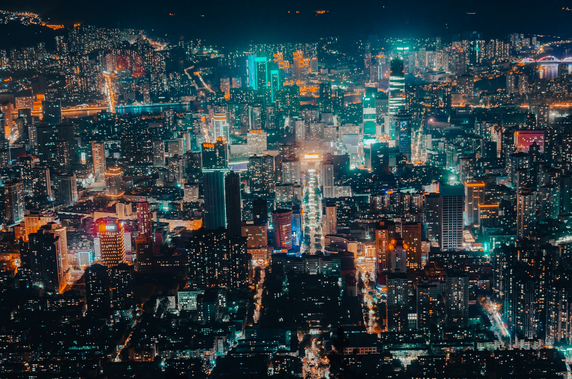 A bustling cityscape at night, illuminated by colorful lights and busy streets.