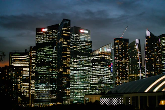 A sleek, modern office skyline at dusk with golden lights reflecting on glass buildings, symbolizing global commerce and trust.
