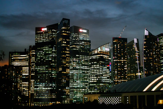 A sleek, modern office skyline at dusk with golden lights reflecting on glass buildings, symbolizing global commerce and trust.