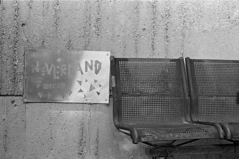 a black and white photo of a bench and a sign