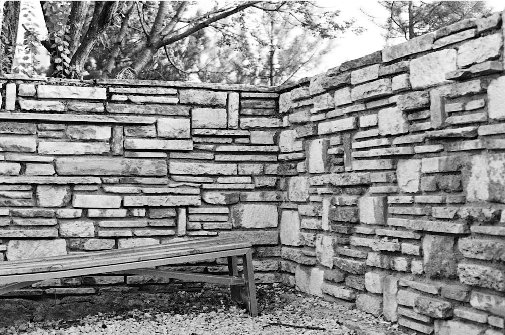 a black and white photo of a bench in a brick wall