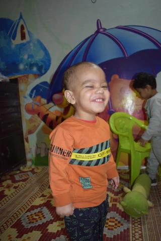 Smiling caregivers interacting warmly with toddlers in a colorful play area.