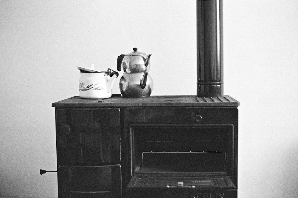 a black and white photo of a stove with a kettle on top of it