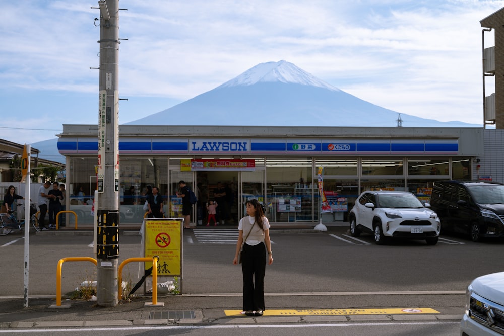 a woman standing in front of a store with a mountain in the background