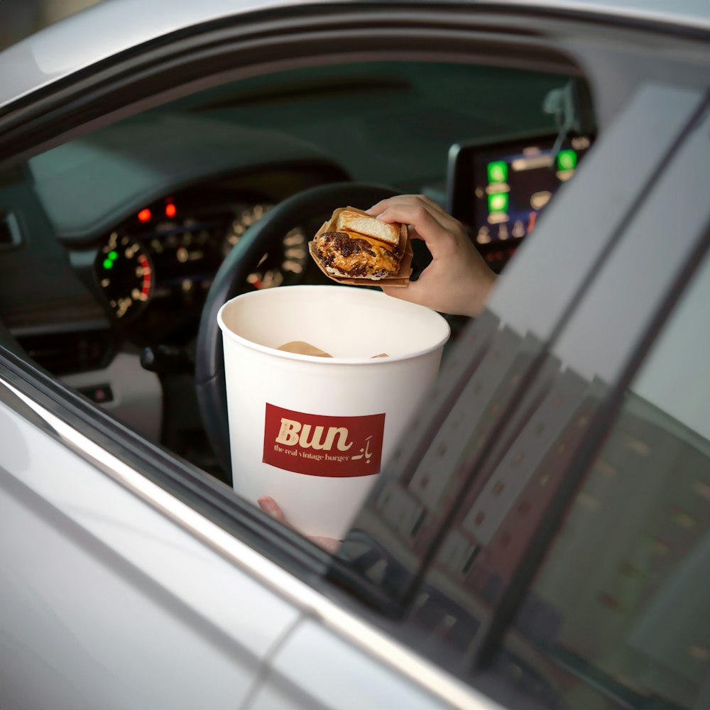 a person sitting in a car holding a cup of coffee