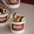 A white container labeled 'Bun, the real vintage burger' contains two sandwiches, each cut in half and partially wrapped in brown paper. Another identical container with the same label is being held in the background.