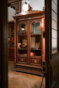 A vintage wooden cabinet filled with carefully restored curios and delicate collectibles under warm light.