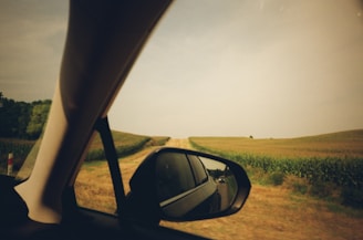 a side view mirror of a car on a dirt road