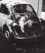 A gleaming vintage Beetle parked under soft sunlight at a lively club meet.