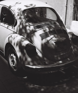 A sleek, minimalist photo of a vintage Volkswagen Beetle parked on a sunlit street.