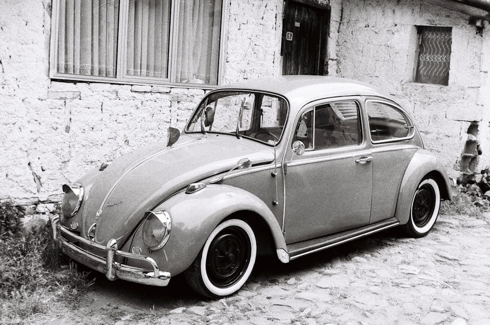 a black and white photo of a car parked in front of a building