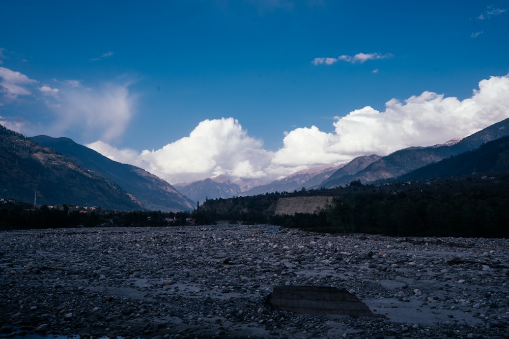 a rocky river with mountains in the background