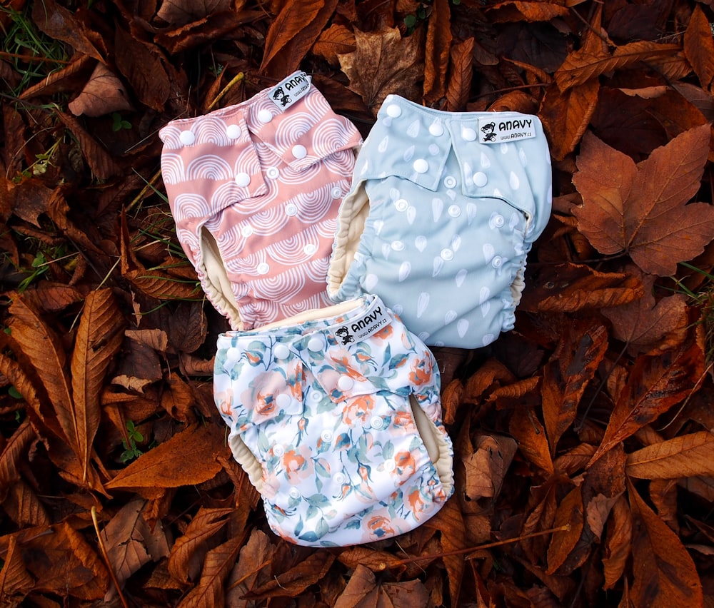 three diapers laying on top of leaves on the ground