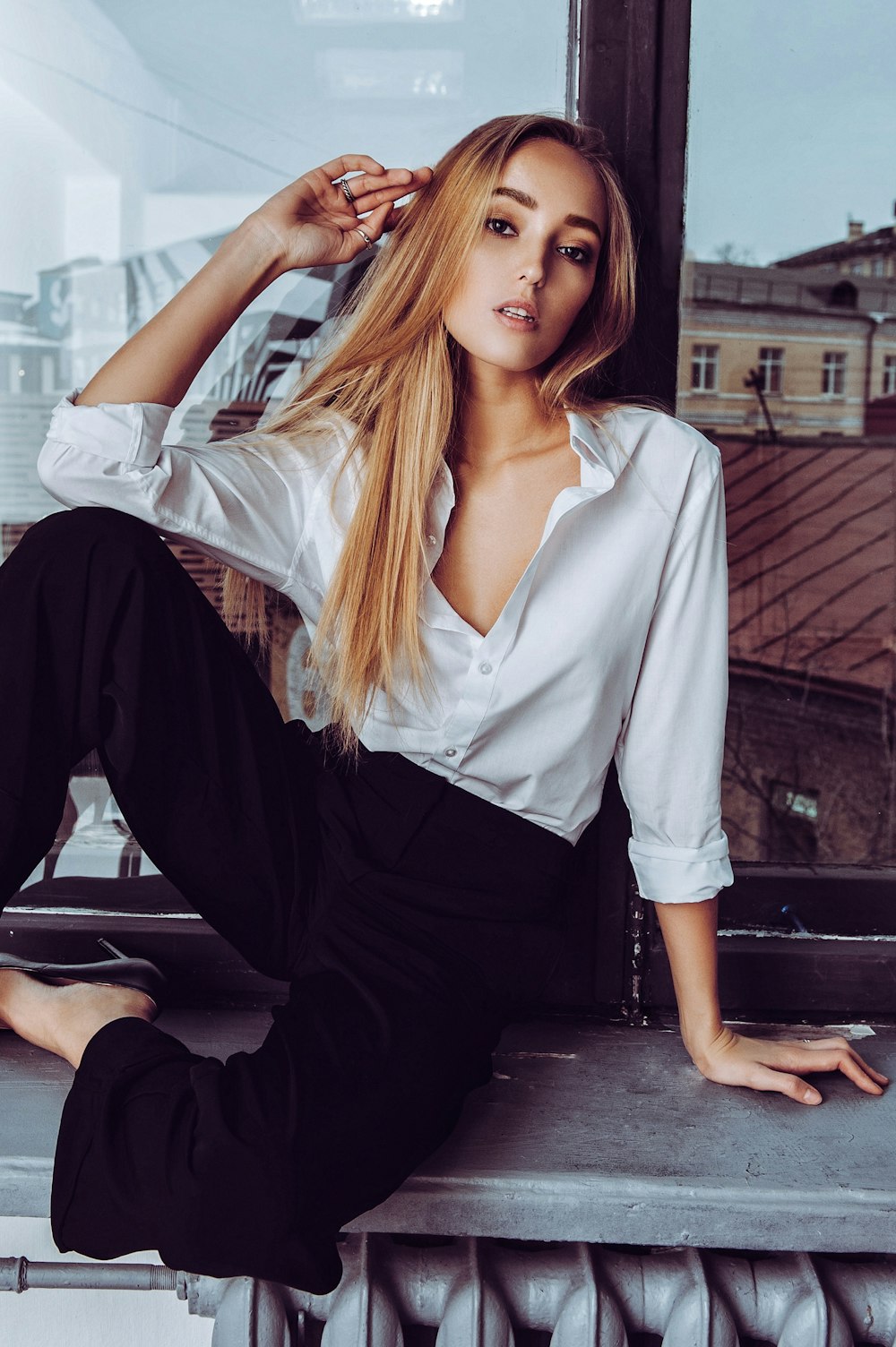 a woman sitting on a window sill posing for a picture