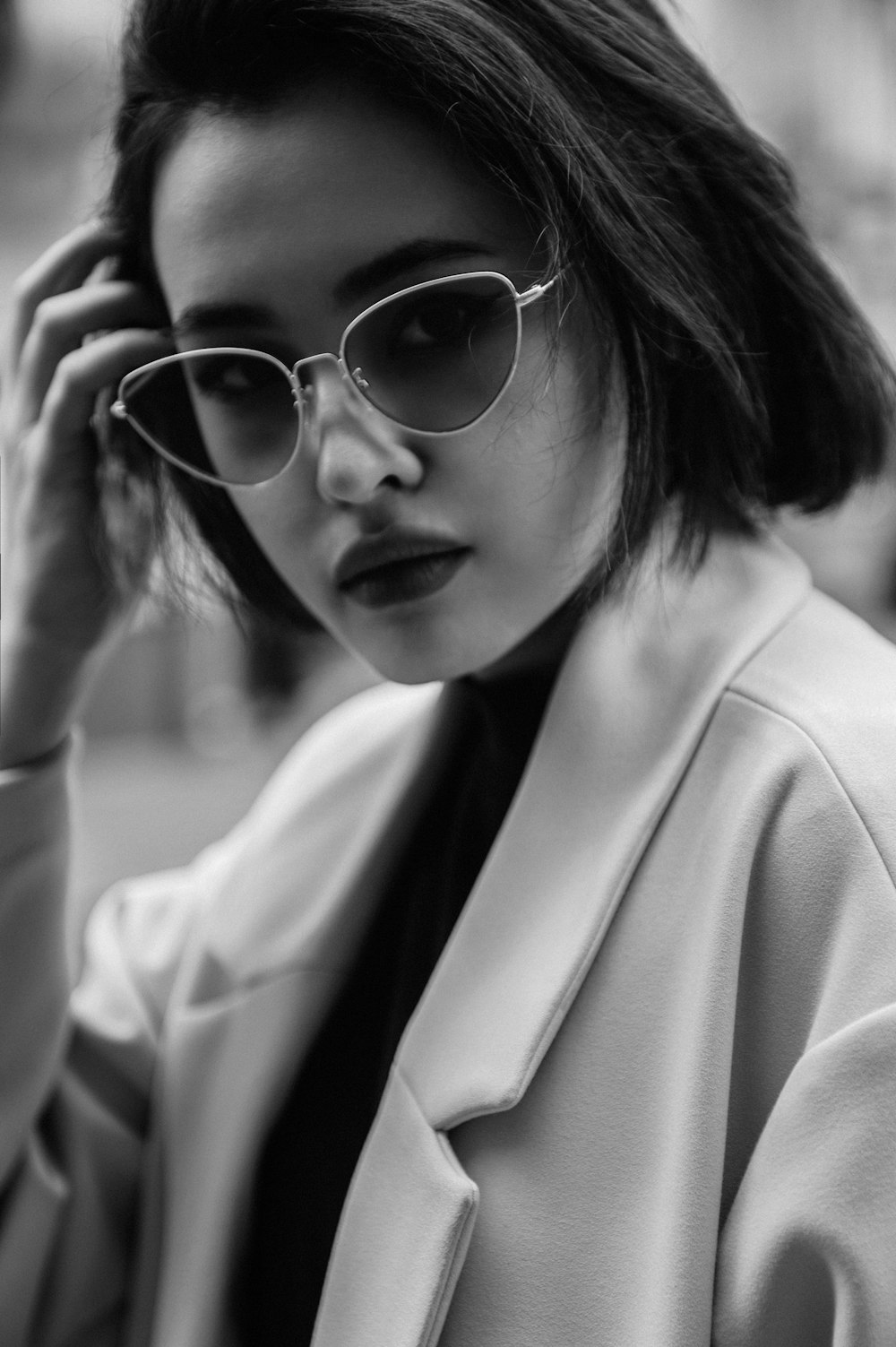 a woman in a white coat and sunglasses