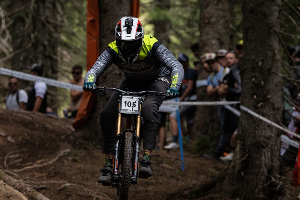 a man riding a bike through a forest filled with people