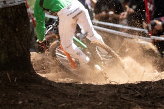 Action shot of a rider powering through a technical rock garden, dust and leaves kicking up behind.