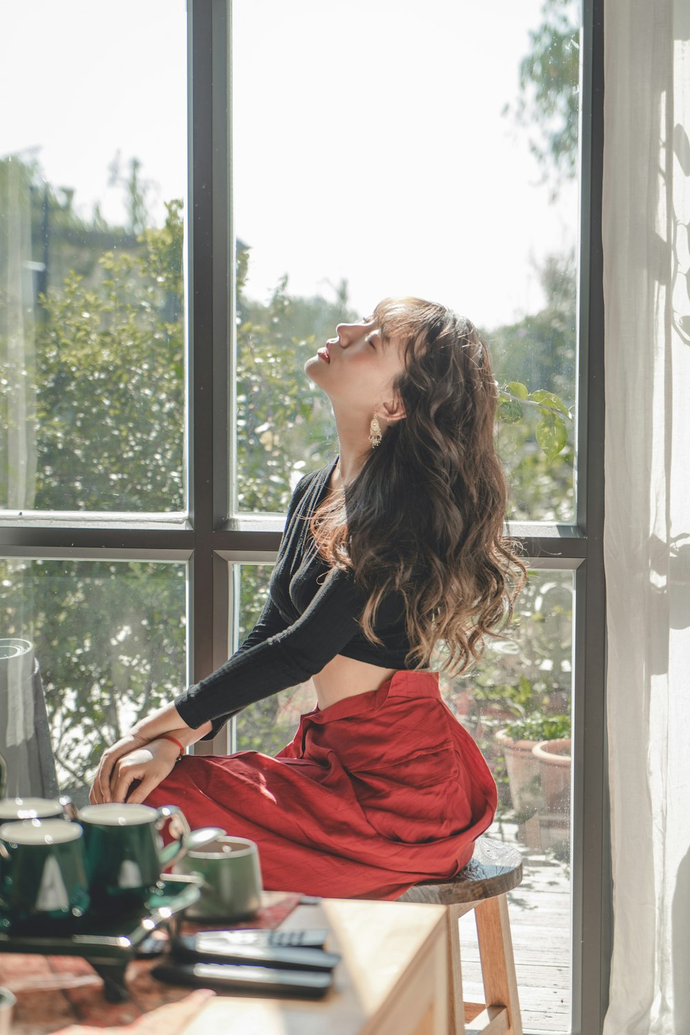 a woman sitting on a stool looking out a window