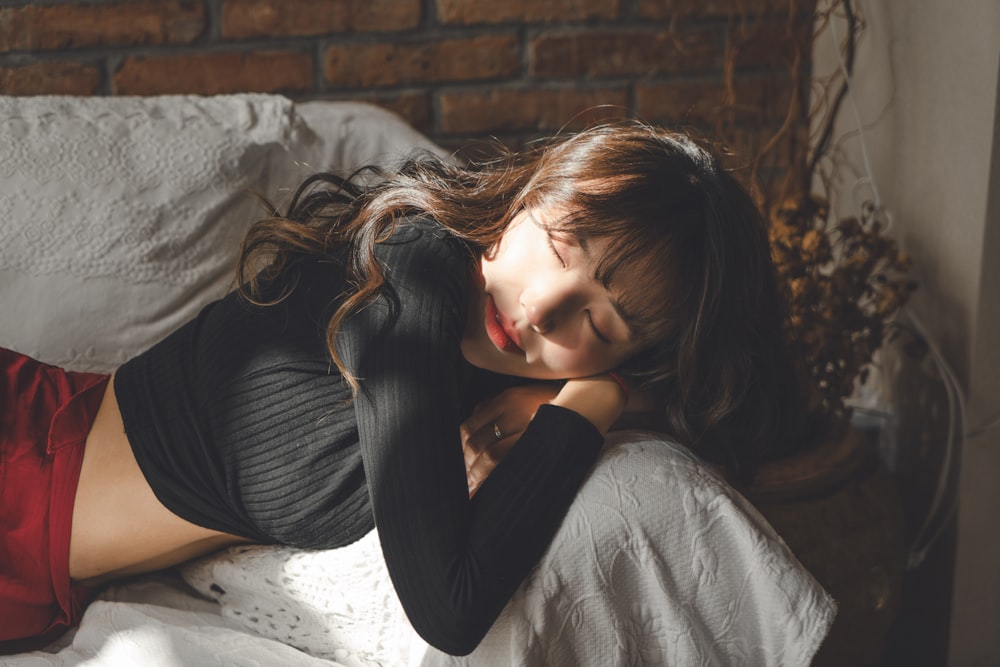 a woman laying on top of a bed next to a brick wall