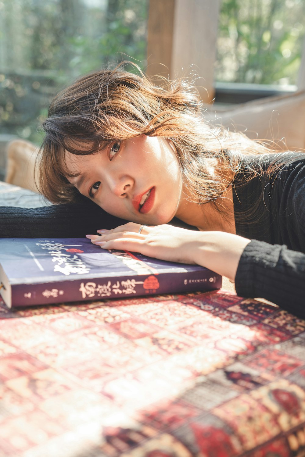 a woman laying on top of a bed next to a book