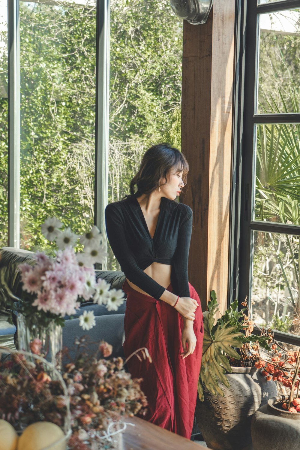 a woman standing in front of a window next to flowers