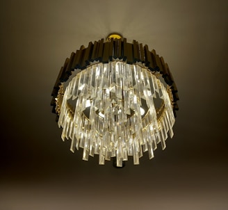 A luxurious chandelier with multiple layers of crystal prisms hangs elegantly from the ceiling. The dark frame contrasts with the bright, sparkling crystals that catch and reflect light beautifully.
