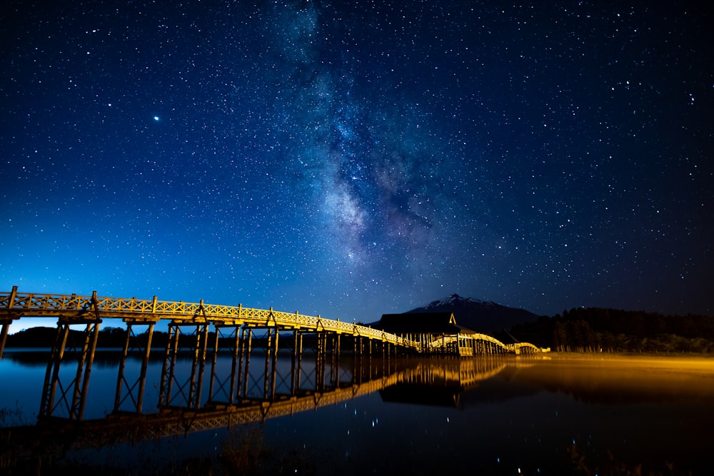 a night time view of a bridge and the milky