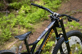 Close-up of a mountain bike frame made from recycled aluminum under a forest canopy.