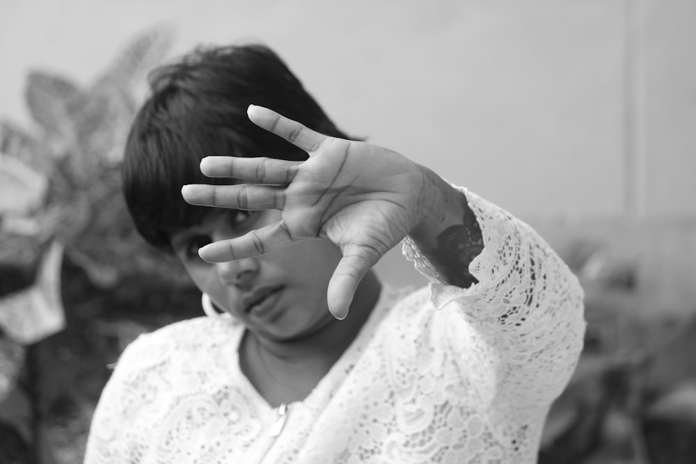 a black and white photo of a woman making a hand sign