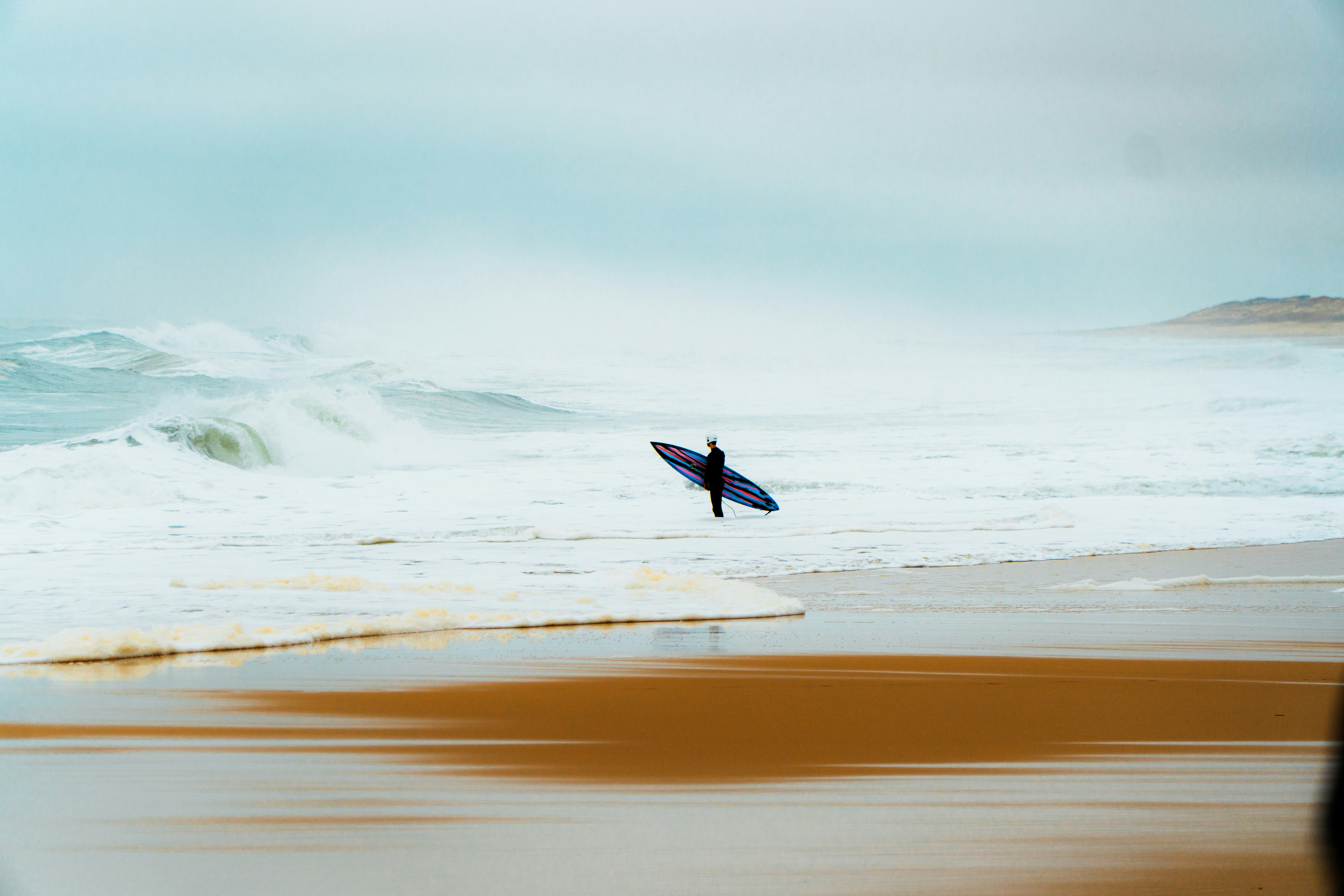 a person holding a surfboard on a beach