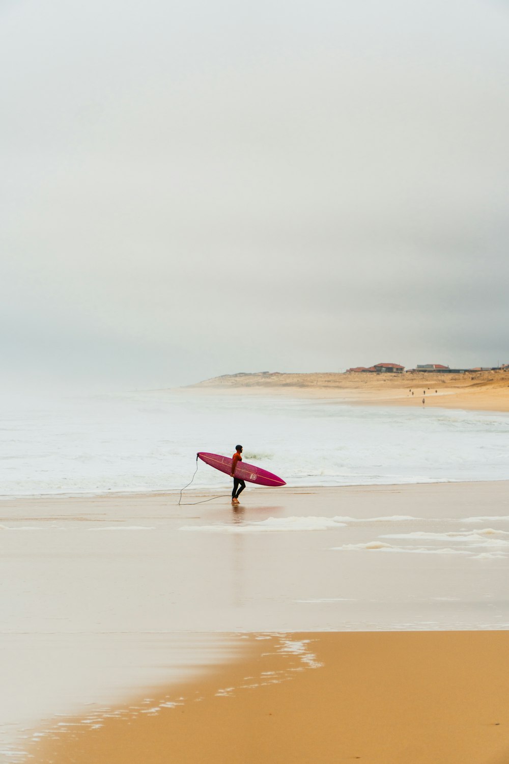 a man carrying a surfboard across a sandy beach