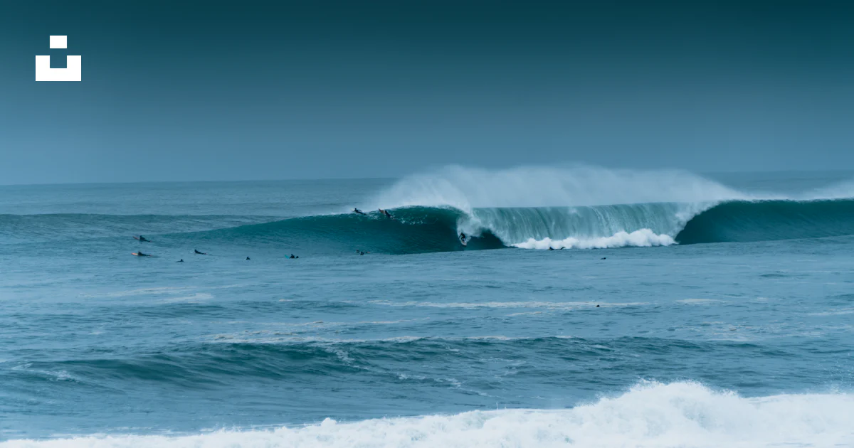 Two surfers are riding a large wave in the ocean photo – Free France ...